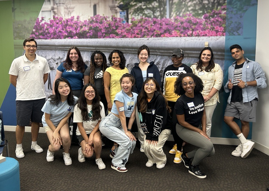 13 students smiling and standing in front of a mural of azalea flowers