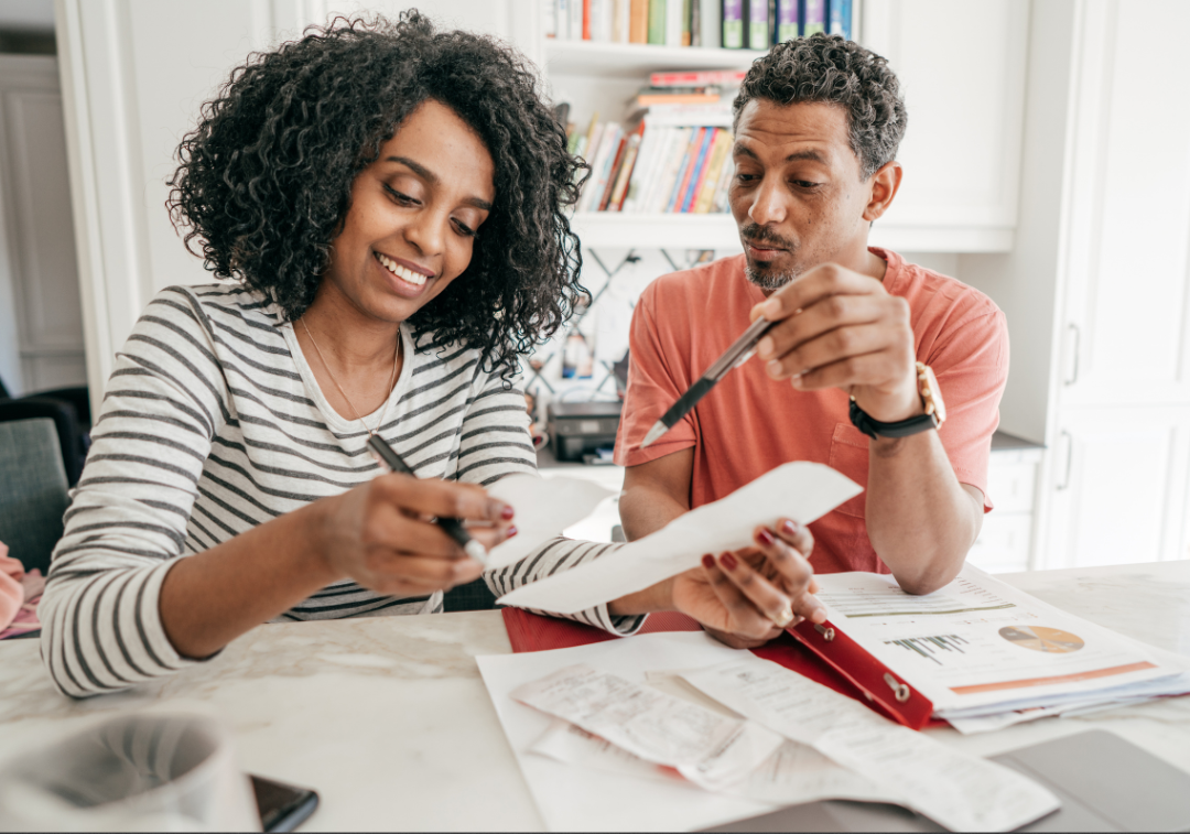 Smiling woman and man review documents and bills at a table.