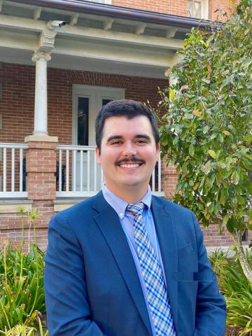 man standing in front of building with porch and tree